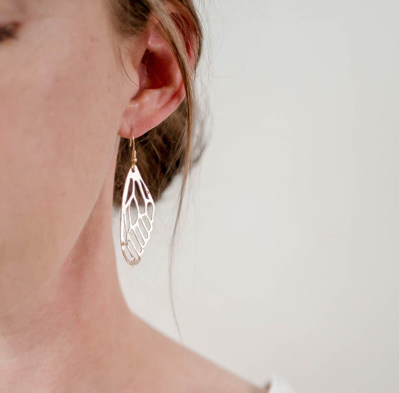 Close up of woman's ear and neckline wearing gold plated handcrafted dragonfly wing dangle earrings by Krista Knickerbocker Designs.