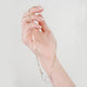Woman's hand holding delicate gold filled elongated hoop chain with handmade sterling silver hook clasp.