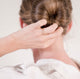The back of a woman's head with a clean bun and her hand touching her hair while wearing a handcrafted double band gold vermeil ring by Krista Knickerbocker Designs.