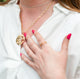 Close up of woman wearing a white shirt with a pink manicure and wearing handcrafted gold vermeil jewelry by Krista Knickerbocker Designs including the Water Reflection circular double layer pendant and the handcrafted double band ring.