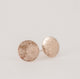 Close up photo of gold circle textured post earrings on a white table.  Handcrafted textured stardust earrings by Krista Knickerbocker Designs.