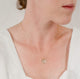 Close up of woman's neck wearing a dainty textured handcrafted 14k gold vermeil circle pendant necklace by Krista Knickerbocker Designs.