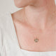 Close up of woman's neck wearing a dainty textured handcrafted 14k gold vermeil circle pendant necklace by Krista Knickerbocker Designs.