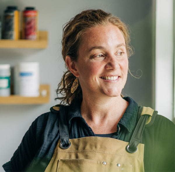 Jewelry designer Krista Knickerbocker Designs in her studio looking out the window and wearing her dragonfly wing dangle earrings.