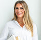 Beautiful smiling woman wearing a white collared shirt and shiny gold handcrafted gold necklace by Krista Knickerbocker Designs.