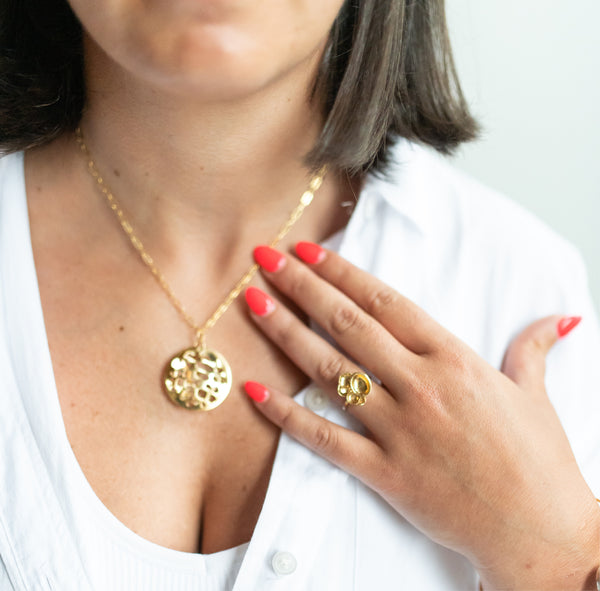 Zoom in of woman in white top with pink manicure wearing large 14k gold porous double layered water reflection necklace and 14k gold vermeil cluster ring both by Krista Knickerbocker Designs.