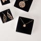 Various pieces of 14k gold vermeil handcrafted jewelry in jewelry boxes with black foam inserts, all handcrafted by Krista Knickerbocker Designs.  Pieces include dragonfly wing dangle earrings, textured circle "stardust" pendant, and layered porous water reflection necklace.