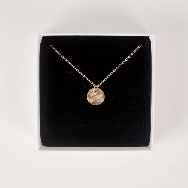 Close up of handcrafted textured 14k gold vermeil circle pendant necklace on black foam inside of a Krista Knickerbocker Designs jewelry box.