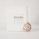 White cardboard jewelry box with gold embossed  name Krista Knickerbocker and a handcrafted, layered, 14 karat gold vermeil calm waters necklace by the designer draped over the box.