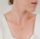 Close up of woman's neck wearing a dainty textured handcrafted 14k gold vermeil circle pendant necklace by Krista Knickerbocker Designs. 