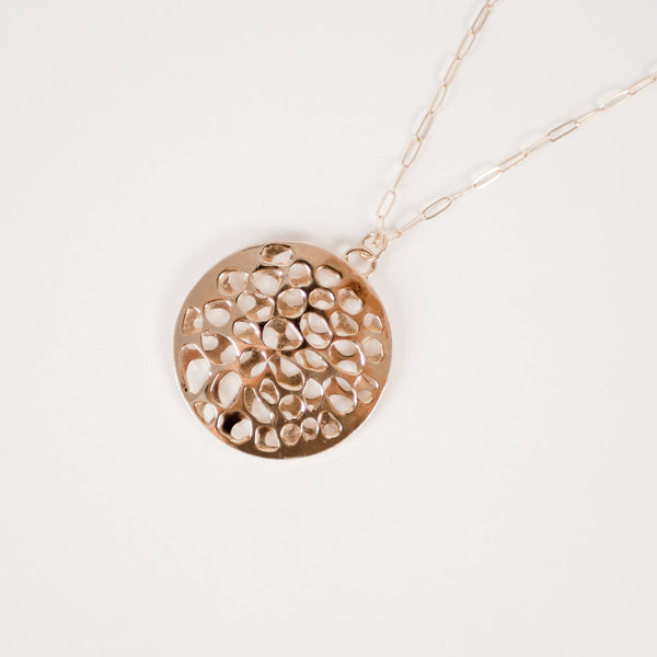 Close up of handcrafted layered circle 14k gold vermeil pendant by Krista Knickerbocker Designs on a white background showing the porosity and depth of the piece. 