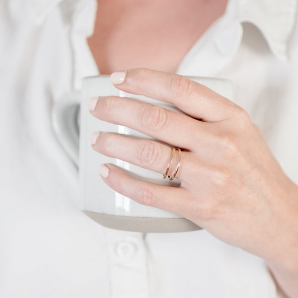 Woman wearing a white button down shirt, with a white manicure, holding a white ceramic mug and wearing Krista Knickerbocker Designs' handcrafted double band gold vermeil ring. 